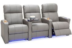 three reclining chairs with remotes on each side and a table in the middle