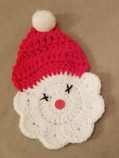 a crocheted santa claus hat laying on top of a brown surface with a red nose