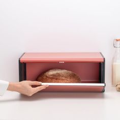 a person holding a piece of bread in front of a toaster