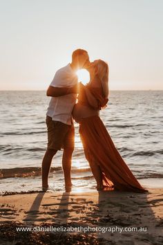 a couple kissing on the beach at sunset