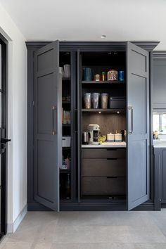 an open cabinet in the middle of a kitchen with gray cabinets and drawers on both sides