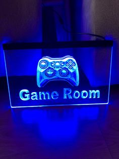 a neon sign that says game room with a video game controller in the center and blue lights behind it