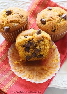 three chocolate chip muffins sitting on top of a red napkin