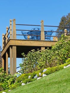 a wooden structure with blue chairs on top of it in the middle of a grassy hill