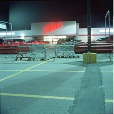 an empty shopping cart sitting in front of a store with cars parked outside the building