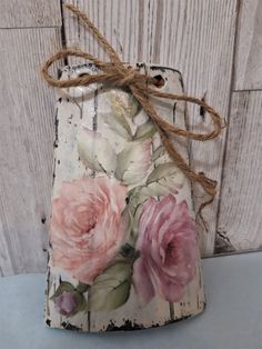 a small bag with flowers painted on it and tied to a wooden board wall behind it