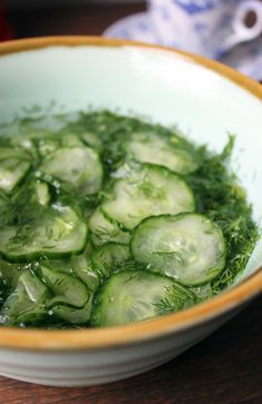 a bowl filled with cucumbers and water on top of a wooden table