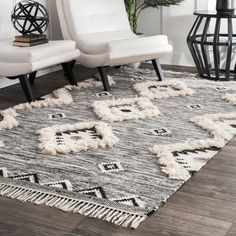 a white chair sitting on top of a wooden floor next to a black and white rug