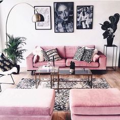 a living room with pink couches and pictures on the wall above them, along with rugs