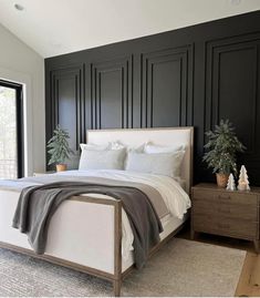 a bedroom with black paneled walls and white bedding