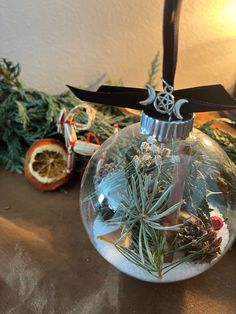 a glass ornament filled with air plants and pine cones on top of a table