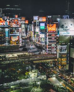 an aerial view of a city at night with lots of lights and billboards on the buildings