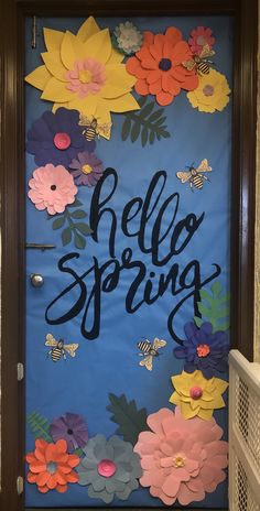 a door decorated with paper flowers and the words hello spring written in cursive writing