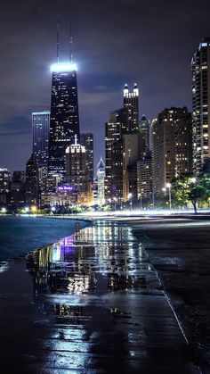 the city skyline is lit up at night with lights reflecting in the water and skyscrapers