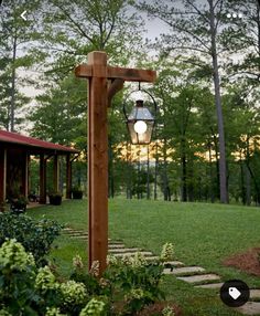 a wooden post with a lantern hanging from it's side in the middle of a yard