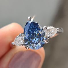 a blue diamond surrounded by three white diamonds is being held in someone's hand