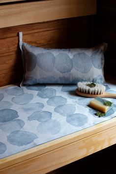 a wooden bed with a blue and white patterned pillow on top of it next to a brush