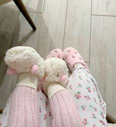 two stuffed animals sitting on top of someone's legs in pink and white socks