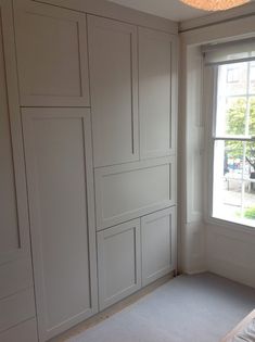 an empty room with white walls and cupboards on the wall, in front of a window