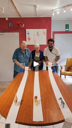 three people standing around a large wooden table