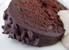 a piece of chocolate cake sitting on top of a white plate next to a cookie