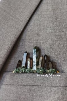 a boutonniere made out of wood sticks and greenery sits on a suit jacket lapel