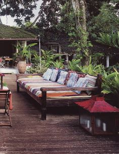 an outdoor seating area with lots of pillows on the couches and tables around it