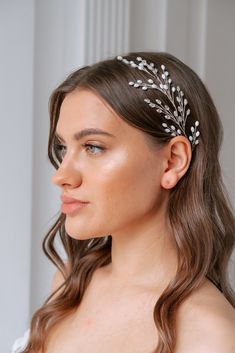 a woman with long hair wearing a white headband and silver leaves on it's side