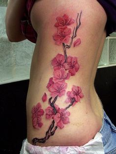 a woman's lower back tattoo with pink flowers on it