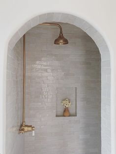 a bathroom with white tile and gold faucet in the shower head is shown