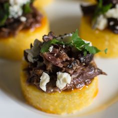 small appetizers with meat, cheese and herbs on them sit on a white plate