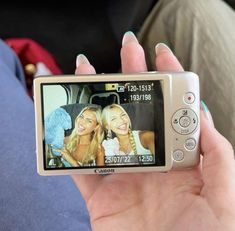 a person holding up a cell phone with two girls on it