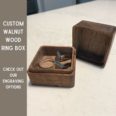 a wooden ring box sitting on top of a white counter next to a pair of scissors