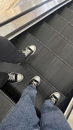 someone is standing on an escalator with their feet in the air while wearing sneakers