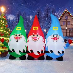 three inflatable christmas gnomes are standing next to a christmas tree on the snow