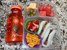 a plastic container filled with fruit and crackers next to a bottle of water on top of a counter