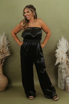 Elevate your fall wardrobe with the "Here To Impress Satin Jumpsuit." Crafted from luxurious satin, this versatile piece offers timeless elegance and a flattering fit, making it the perfect choice for your fall 2023 events and special occasions. Neckline: Strapless Fabric: 100% Polyester; Lining: 100% Polyester Sleek fabrication Wide leg bottom Cinched waistline Imported Fit: True to size! Chest: Relaxed Stretch only in the waistband Measurements: Measured lying flat - Some stretch in waist + chest S: Bust: 23” | Waist: 24” | Rise: 12 1/2” | Inseam: 30” | Length: 52” M: Bust: 25” | Waist: 26” | Rise: 13” | Inseam: 31” | Length: 52 1/2” L: Bust: 27” | Waist: 28” | Rise: 13 1/2” | Inseam: 32” | Length: 53” Model Specs: Emily + Karli are wearing a size small in the photo.How will this item fi Black Satin Jumpsuits And Rompers For Evening, Party Satin V-neck Jumpsuits And Rompers, Chic Satin Jumpsuits And Rompers With V-neck, Black Full-length Satin Pants, Black Satin Evening Jumpsuit/romper, Satin Jumpsuit, Jumpsuit Black, Everyday Chic, Holiday Looks