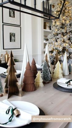 a christmas tree sitting on top of a wooden table next to plates and napkins