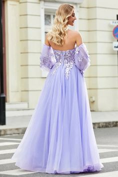 a woman in a purple dress is walking down the street with her back to the camera