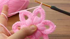 someone is crocheting a pink flower with yarn