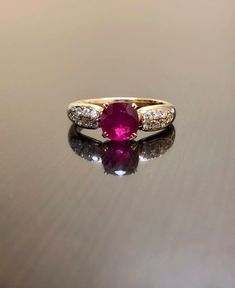 DeKara Designs Collection Metal- 18K Yellow Gold, .750. Stones- 1 Oval Ruby 1.05 Carats, 14 Round Diamonds G-H Color VS2 Clarity 0.25 Carats. Art Deco 18K Yellow Gold Ruby Diamond Engagement Ring. This ring features a beautiful reddish pink ruby that is professionally set in between four prongs. There are seven pave set diamonds on each side of the ruby. The yellow gold and the ruby compliment one another beautifully and the diamonds are the perfect finish to this amazing ring. Size- 7 1/2. FREE Luxury Ruby Ring With Diamond Accents And Round Shape, Luxury Yellow Gold Ruby Ring With Diamond Accents, Luxury Round Ruby Ring With Diamond Accents, Luxury Ruby Ring With Diamond Accents In Yellow Gold, Luxury Yellow Gold Ruby Ring With Center Stone, Classic Gia Certified Round Ruby Ring, Anniversary Yellow Gold Gia Certified Ruby Ring, Gia Certified Yellow Gold Ruby Ring For Anniversary, Fine Jewelry Gold Ruby Ring Gia Certified