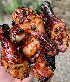 a hand holding up some chicken wings covered in bbq sauce