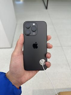 a person holding an iphone in their hand with earbuds attached to the back