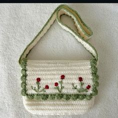 a crocheted purse with red flowers on the front and green trimmings