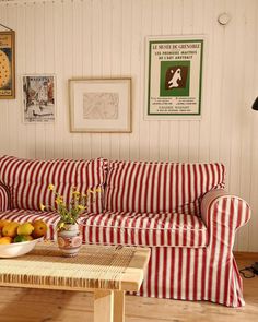 a red and white striped couch sitting in a living room next to a coffee table