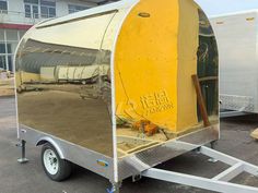 a yellow trailer parked in a parking lot next to a building with windows on the side