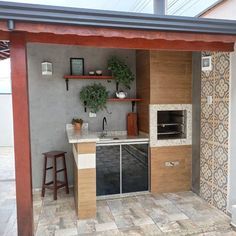 an outdoor kitchen with tile flooring and wooden shelves on the wall, along with potted plants