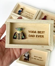 a hand holding a wooden box with an image of yoda best dad ever in it