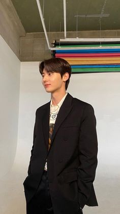 a young man in a suit and tie standing next to a wall with multicolored lines on it