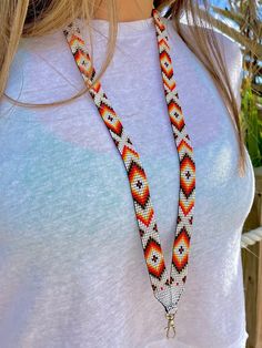 a woman wearing a white shirt and necklace with an orange, red and black beaded design